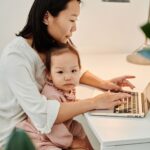 Parent working on a laptop at home while caring for a child
