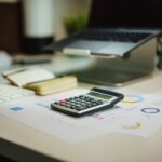 Calculator and laptop used to figure 2027 payroll and self-employment tax under the new Social Security wage base