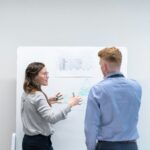 Two colleagues reviewing R&D project notes on a whiteboard, representing Texas and Colorado research and development tax credit planning